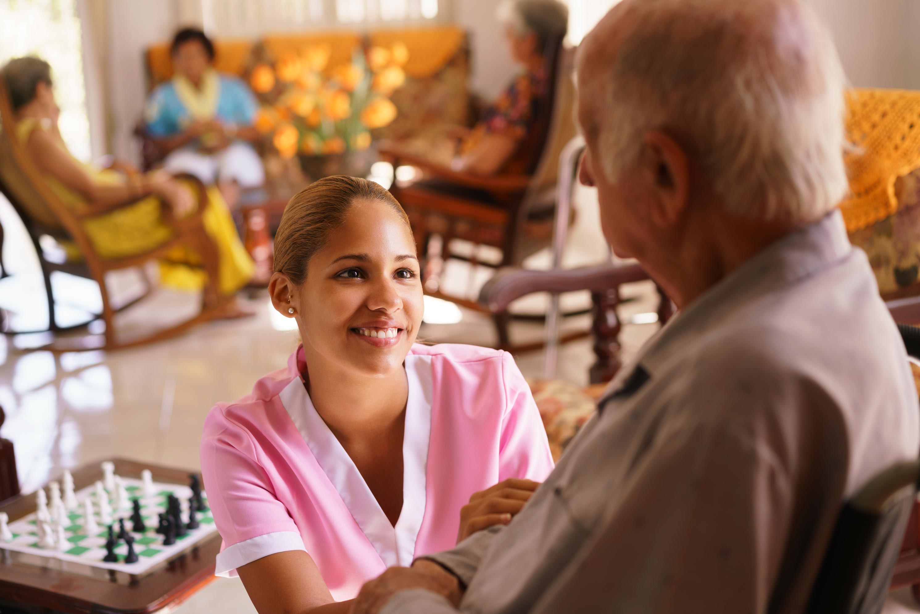 Lady sitting with a care giver in her living room.