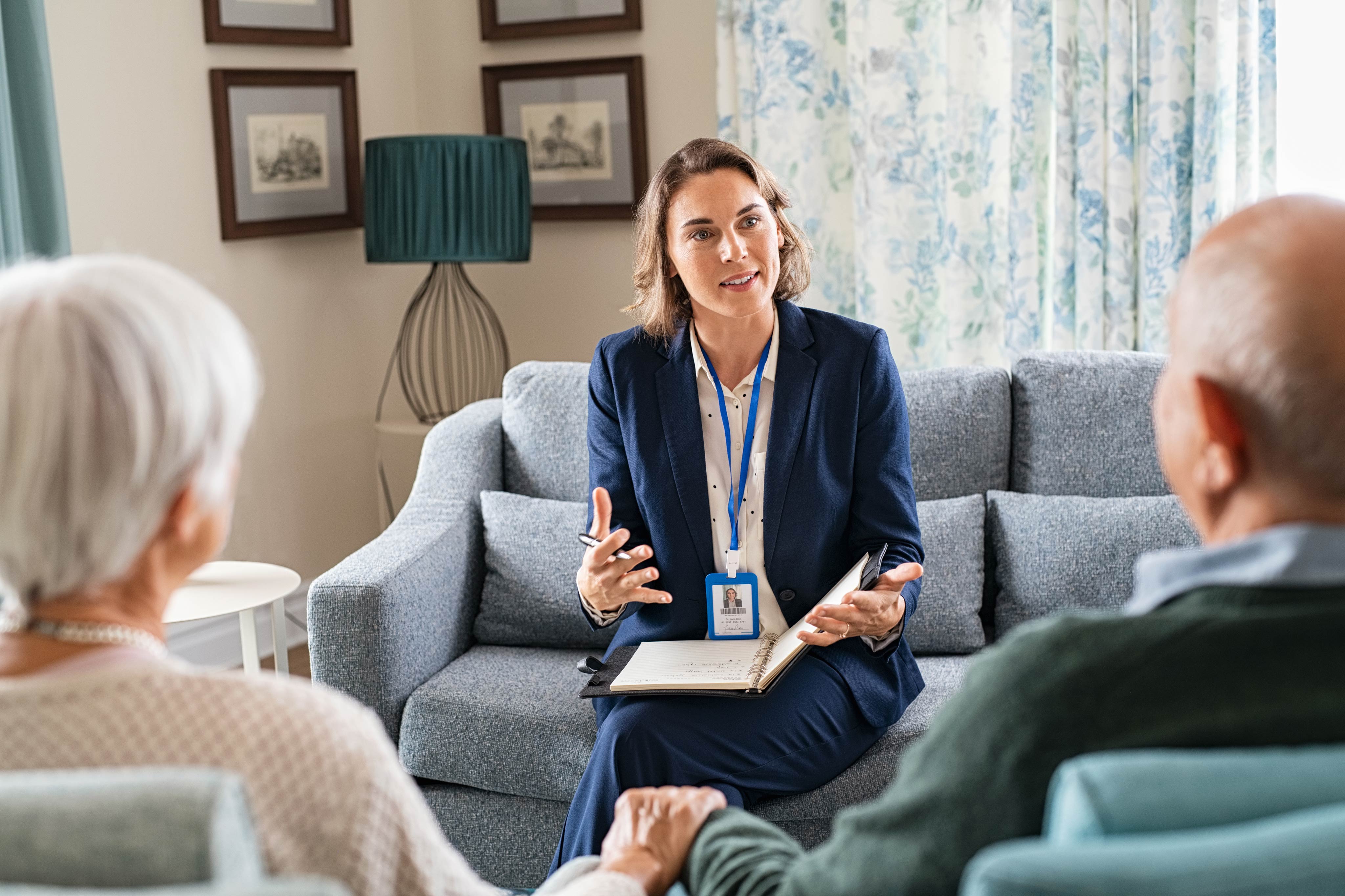 Lady sitting with a care giver in her living room.