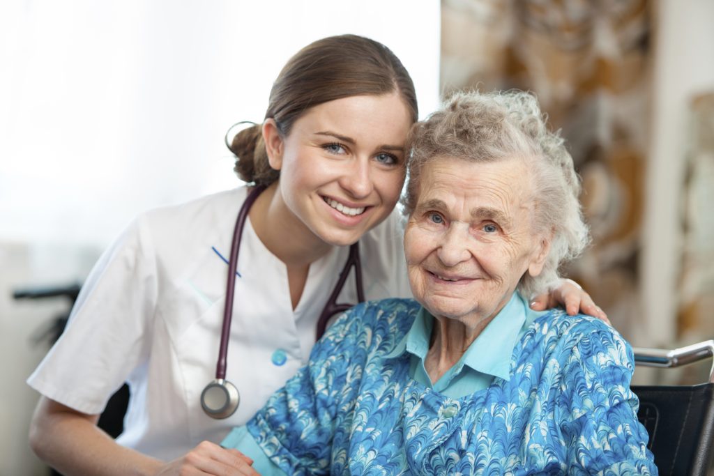 A medical professional smiles with an elderly patient in assisted living 